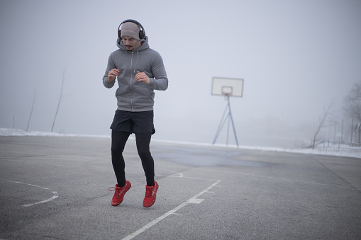 a young man warms up before running in cold foggy weather