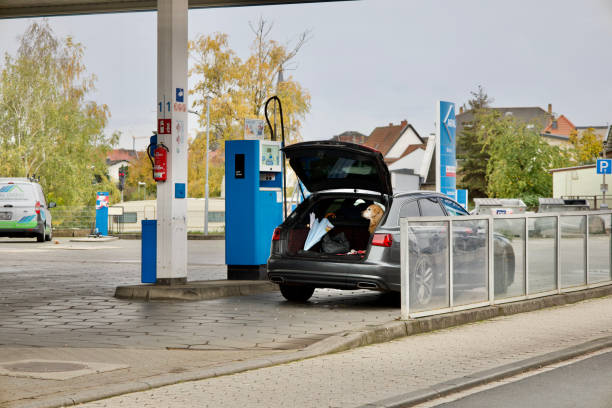 Sedan, Truck and SUV filling up at gas station. Posted prices legible on pumps.