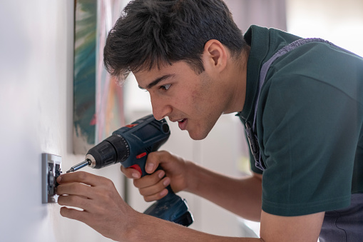 Young repairman repairing electrical outlet at home