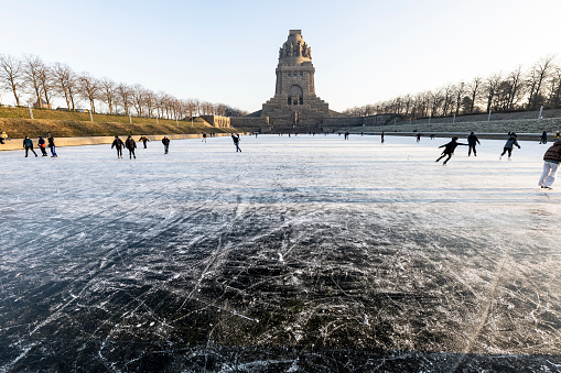 Leipzig, Saxony, Germany on January 11, 2024: people enjoy ice skating at the frozen pond in front of the famous battle of nations monument