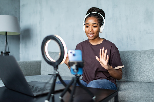 Young adult black woman streaming from home using mobile