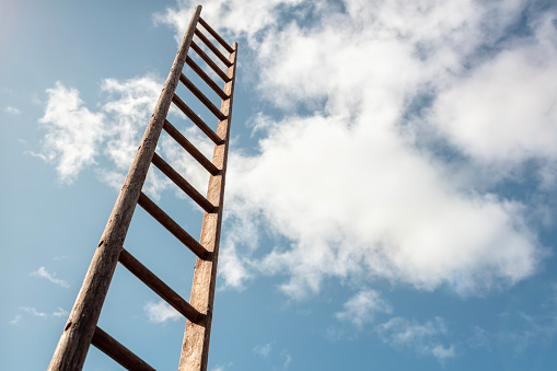 Ladder of success looking up into blue sky with white cloudscape background business career and promotion concept