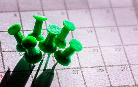 Important date many green thumbtacks in one busy day being fully booked and overworked background