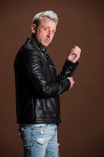 blond man in casual clothes in the studio. leather jacket, ripped jeans and leather boots