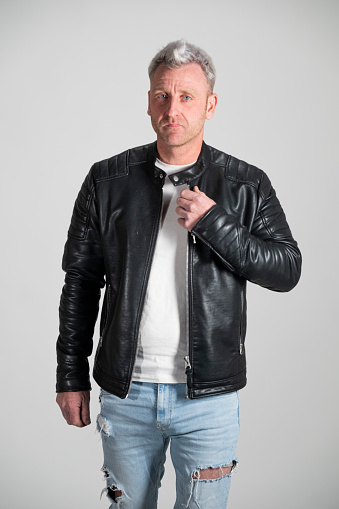 blond man in casual clothes in the studio. leather jacket, ripped jeans and leather boots