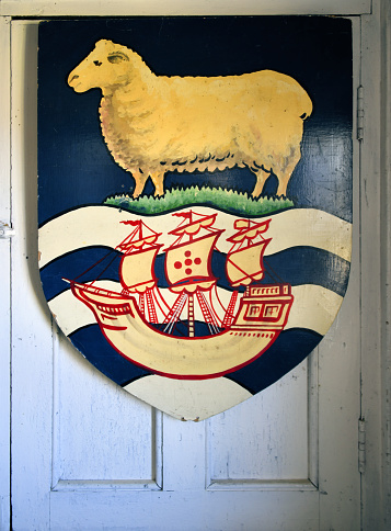 North Arm, Falkland Islands: Falkland Islands coat of arms featuring a ram (symbolic of the sheep-raising industry of the islands), and a ship over waves, representing the Desire which is the ship that discovered the islands in 1592.