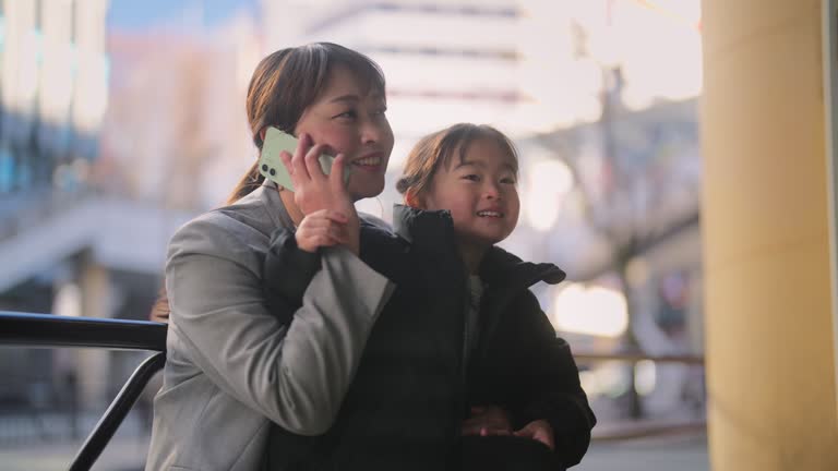 Businesswoman working at bus station while waiting for bus with her daughter