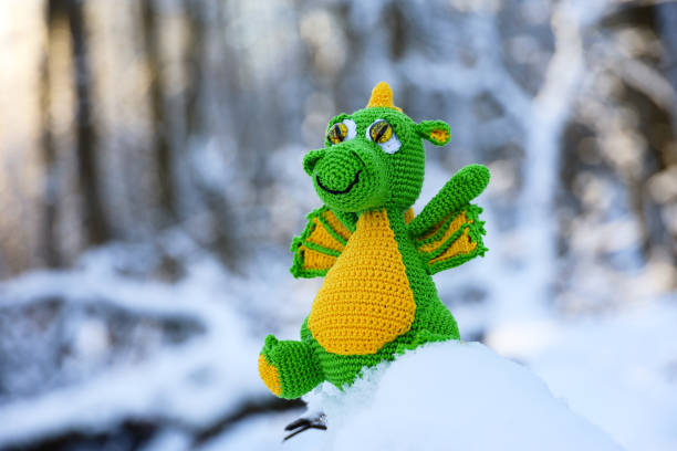 istock Knitted dragon in a snow on winter forest background, greeting card 1927530791
