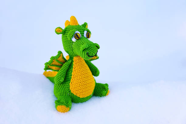 istock Knitted green dragon on snow background 1927530794