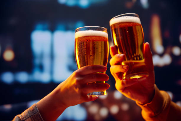 Hands holding lager light foamy big beer glasses and clinking. Two friends sitting in bar and drinking alcohol drinks. Hands holding lager light foamy big beer glasses and clinking. Two friends sitting in bar and drinking alcohol drinks. Concept of Beer Fest, party, celebration, taste, national traditions. toasting stock pictures, royalty-free photos & images