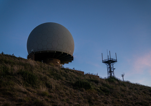 Telecommunications tower with 4g mobile communication antenna on top of a hill. Rural landscape.