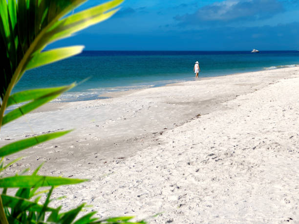 istock Single woman walking on white sandy tropical beach 1927570881
