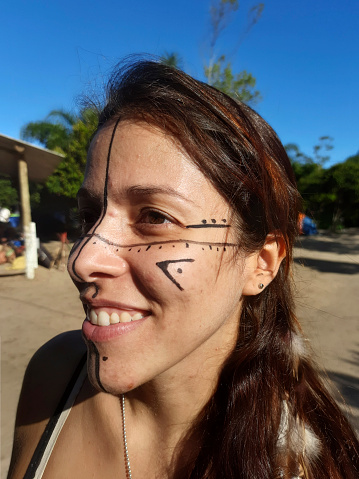 Young Latin woman with face paint typical of the Guarani people of southern Brazil