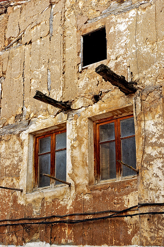 Abandoned structure featuring a dilapidated facade and two windows