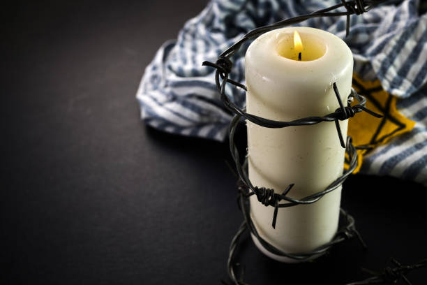 istock Holocaust memory day. Arbed wire and burning candle on black background 1927593458
