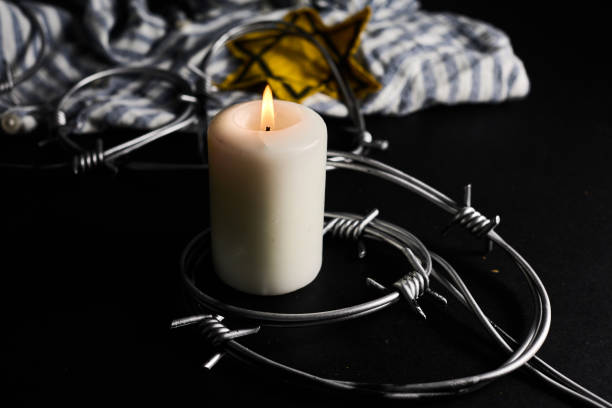 istock Holocaust memory day. Arbed wire and burning candle on black background 1927593590