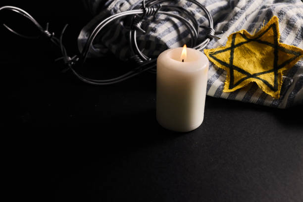 istock Holocaust memory day. Arbed wire and burning candle on black background 1927606330