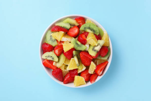 istock Yummy fruit salad in bowl on light blue background, top view 1927611248