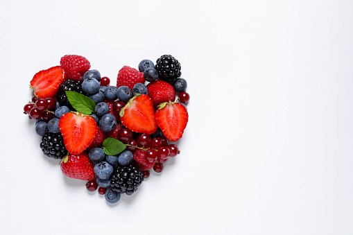 Heart shape made from 49 fruits and vegetables colorful portions on white background.
