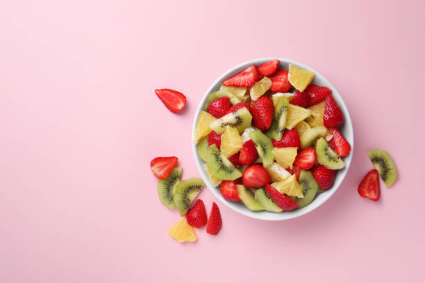 istock Yummy fruit salad in bowl and ingredients on pink background,flat lay. Space for text 1927611903