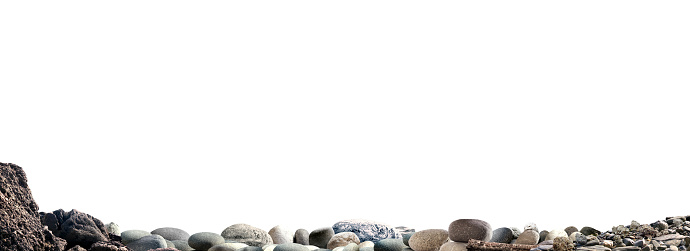 Coral and stones are balanced in a tower on a rocky tropical beach with the ocean and distant mountains visible in the background.