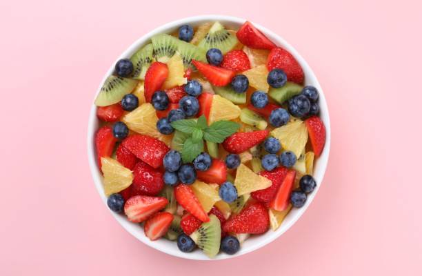 istock Yummy fruit salad in bowl on pink background, top view 1927615017