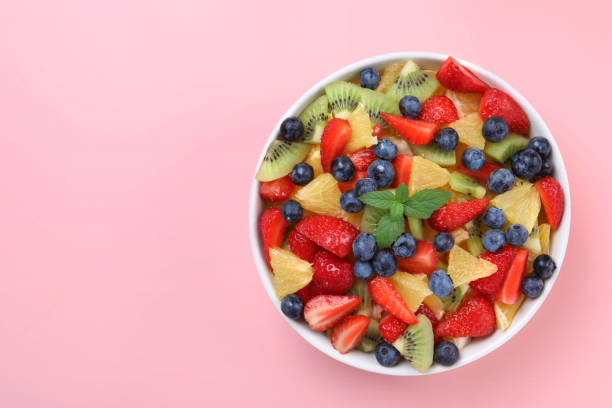 istock Yummy fruit salad in bowl on pink background, top view. Space for text 1927615536
