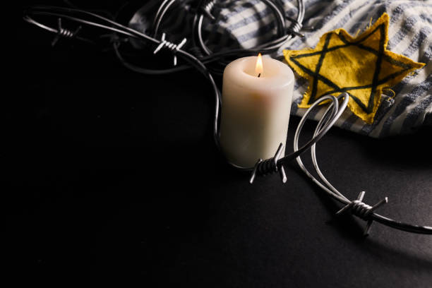 istock Holocaust memory day. Arbed wire and burning candle on black background 1927632105