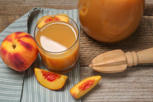 Delicious peach juice, fresh fruits and citrus reamer on wooden table, above view