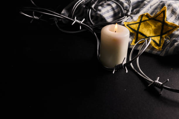 Holocaust memory day. Arbed wire and burning candle on black background