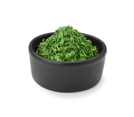 Dried aromatic parsley in bowl isolated on white