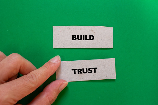 Build trust lettering on ripped paper pieces with green background. Business concept photo. Top view, copy space.