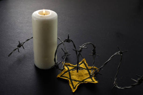 istock Holocaust memory day. Arbed wire and burning candle on black background 1927657443