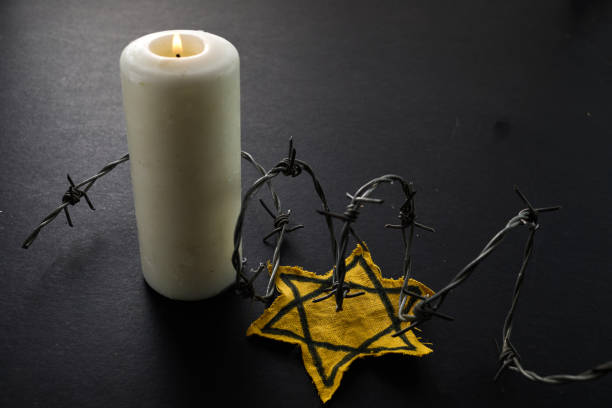 istock Holocaust memory day. Arbed wire and burning candle on black background 1927665979