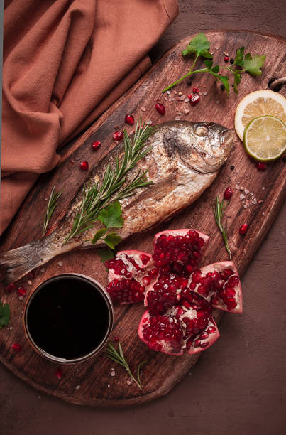 Fried dorado fish, with spices and herbs, on a wooden board, pomegranate sauce, close-up, no people,
