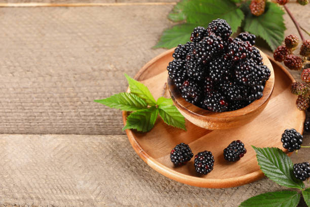 istock Fresh ripe blackberries and leaves on wooden table. Space for text 1927670334