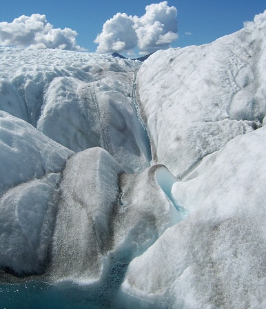 Close-up of a small stream of water which leads to a small pool on the surface of a glacier. Glaciers are greatly impacted by our changing climate. In recent decades, glaciers are losing ice year to year rather than gaining ice, which could threaten water supplies for humans.