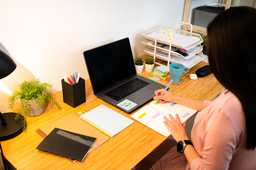 Asian Woman writing her business plan on a book in the home office