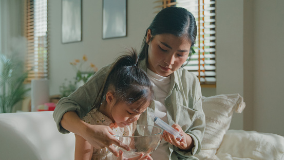 Mom takes Care of her daughter who gets sick and has a high fever, cold, and flu, and does nasal irrigation at home. Illness Girl with a medical condition and family wellness concept.