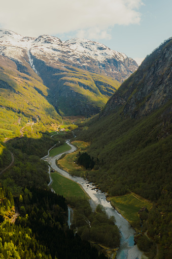 High-angle drone panoramic photo of sunny day over the beautiful valley with river and fresh green mountains in Western Norway, Scandinavia