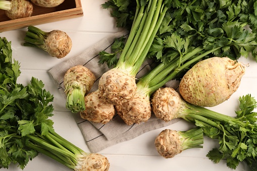 Fresh raw celery roots on white wooden table, flat lay