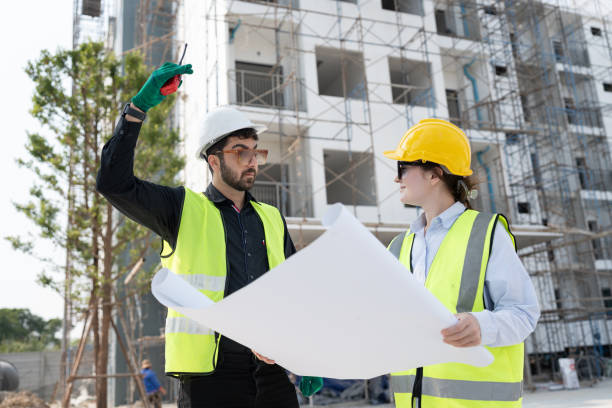 istock Caucasian engineer man and woman working with paper work at construction site 1927702768