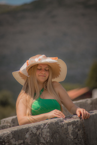 Happy young blonde woman wearing sunhat in hot sunny summer day