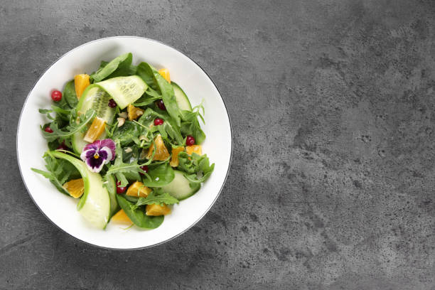 istock Delicious salad with cucumber and orange slices on gray table, top view. Space for text 1927724469