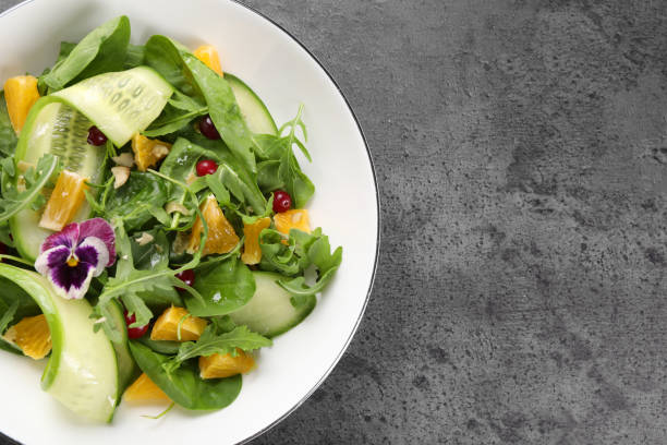 istock Delicious salad with cucumber and orange slices on gray table, top view. Space for text 1927724471