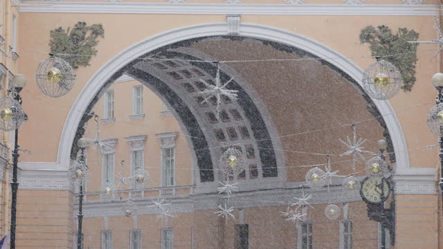 Christmas decorations on the street of the city during the snowfall, Arch of the General Staff on background