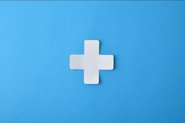 Conceptual medicine symbol with cross shaped paper cutout isolated in the center on blue background.