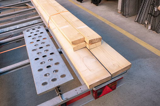 Wooden planks securely fastened to a construction trailer at a building supply store, preparations for either repairs or construction work.