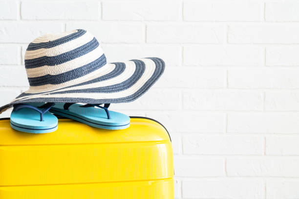 夏休み、旅行のコンセプト。ヤシの葉のスーツケース、帽子、ビーチサンダル。