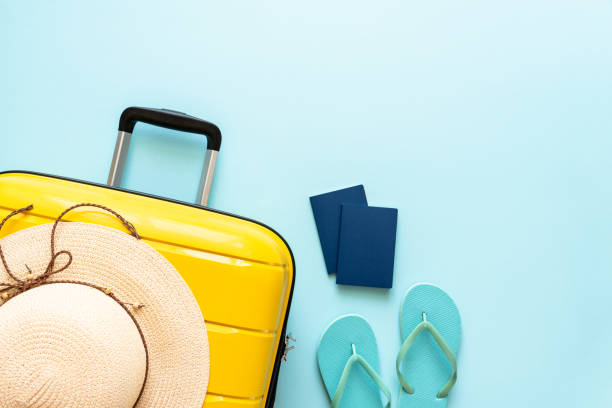 istock Suitcase, hat, passports and flip flops on blue background. 1927790120